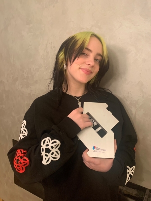 [Billie Eilish pictured with her Official Number 1 Award from the Official Charts Company]